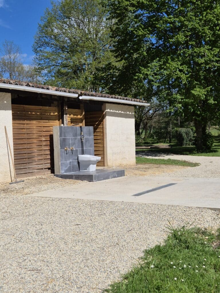 Douche extérieure en pierre près d'un hangar