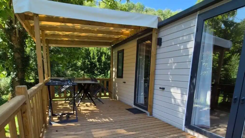 Terrasse en bois avec auvent dans jardin verdoyant.