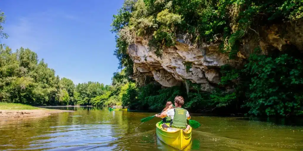 Canoë sur rivière sous falaise verdoyante
