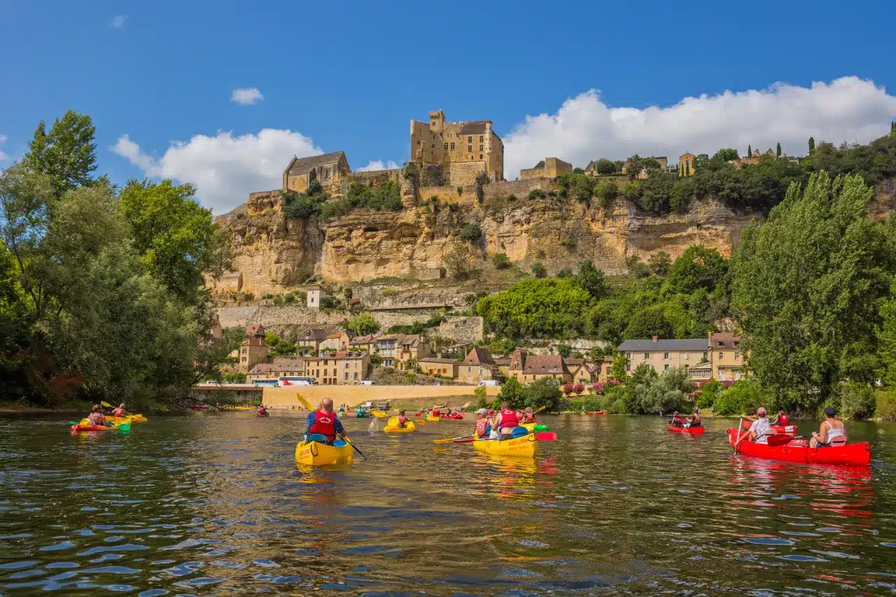 Canoës naviguant sous un château médiéval en Dordogne.