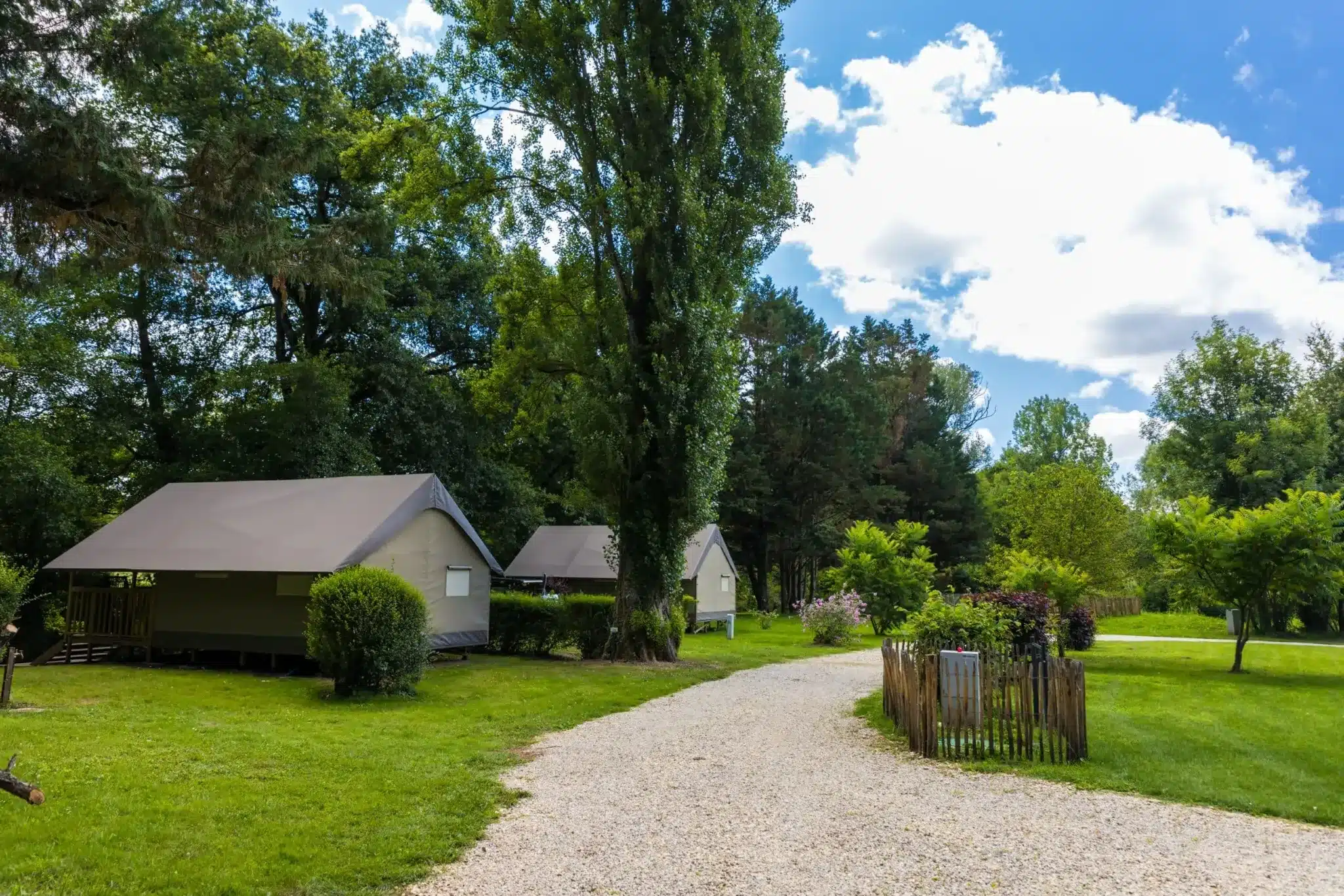 Chemin menant à des tentes dans un camping verdoyant pas cher proche de Périgueux